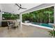 Outdoor patio with dining area, barbecue, and pool surrounded by lush tropical landscaping at 2803 W Aquilla St, Tampa, FL 33629