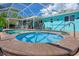 Backyard features a screened pool area, a hot tub, a charming patio, and bright blue siding for ultimate outdoor relaxation at 3243 Azalea Dr, Hernando Beach, FL 34607
