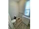 This bathroom features a toilet, wood floor, and cabinet next to a window at 34645 Camphor N Dr, Pinellas Park, FL 33781