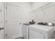 Well-lit laundry room featuring a washer, dryer, and storage shelves at 3655 Moscato Dr, Brooksville, FL 34602