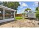 View of the backyard featuring a screened-in porch, carport, wooden fence and a patch of artificial turf at 3850 Carioca Rd, Holiday, FL 34691