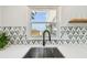 Close-up of modern kitchen sink and faucet with a window and stone backsplash at 3850 Carioca Rd, Holiday, FL 34691