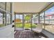 Enclosed sunroom with brick flooring and white seating, offers a tranquil view of the outdoor garden at 3850 Carioca Rd, Holiday, FL 34691