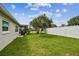 Home and yard featuring vibrant green lawn with mature tree, a white fence, and a screened-in porch at 4108 Woodtrail Blvd, New Port Richey, FL 34653