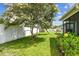 Lush backyard with green grass, blooming hibiscus, a white fence, and a mature tree providing ample shade at 4108 Woodtrail Blvd, New Port Richey, FL 34653
