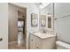 Bathroom view showcasing the vanity with marble countertop and a framed mirror, adjacent to the tiled hallway at 4108 Woodtrail Blvd, New Port Richey, FL 34653