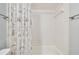 Bright bathroom showcases white tiled walls and a shower-tub combination, complete with a patterned shower curtain at 4108 Woodtrail Blvd, New Port Richey, FL 34653
