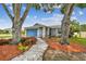 Attractive home with mature trees, landscaping, and a blue garage door at 4108 Woodtrail Blvd, New Port Richey, FL 34653