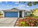 Inviting home with a blue garage door, featuring lush landscaping and a paved walkway at 4108 Woodtrail Blvd, New Port Richey, FL 34653