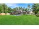 Expansive backyard featuring a screened-in pool area, lush green lawn, and mature trees at 4207 Northwind Ln, Tampa, FL 33624