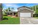 Inviting two-story house featuring a brick facade, attached garage, and lush front yard landscaping at 4207 Northwind Ln, Tampa, FL 33624