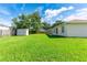 Spacious backyard featuring a lush green lawn, storage shed, and a wood privacy fence at 4928 Timber Way, Zephyrhills, FL 33542