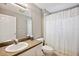 Neutral bathroom featuring a patterned shower curtain, granite-look vanity, and updated light fixture at 4928 Timber Way, Zephyrhills, FL 33542