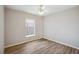 Bright bedroom with plank flooring, neutral walls, and a sunlit window with black shutter blinds at 4928 Timber Way, Zephyrhills, FL 33542