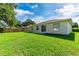 Back of the house with a sliding door, window, well-maintained lawn and partial fence at 4928 Timber Way, Zephyrhills, FL 33542