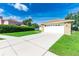 Home's front yard with a long driveway leading to a two-car garage at 4928 Timber Way, Zephyrhills, FL 33542