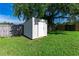 Durable shed with white sliding doors nestled in the backyard by mature shade trees at 4928 Timber Way, Zephyrhills, FL 33542