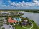 Aerial view of the community pool with lounge chairs, palm trees, and a playground, next to a lake at 5329 Senza Trl, Palmetto, FL 34221