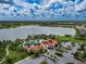Aerial view of community pool, playground, and clubhouse next to a large lake with palm trees and landscaping at 5329 Senza Trl, Palmetto, FL 34221