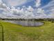 A scenic view of a calm lake surrounded by green grass and several houses at 5329 Senza Trl, Palmetto, FL 34221