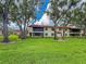 Expansive green lawn surrounded by mature trees and the residential building with screened balconies on a bright day at 5785 Gardens Dr, Sarasota, FL 34243