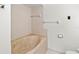 Bathroom features a jacuzzi tub with beige tile surround, handrails, and toilet paper holder at 5785 Gardens Dr, Sarasota, FL 34243