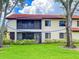 Residential building with red roof tiles, screened balconies and lush landscaping on a bright, sunny day at 5785 Gardens Dr, Sarasota, FL 34243