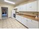 The kitchen has all-white cabinetry, coordinating appliances, and tiled floors, perfect for cooking and storage at 5785 Gardens Dr, Sarasota, FL 34243