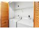 The laundry room offers a washer, dryer, wood-slatted door, and wire shelving above at 5785 Gardens Dr, Sarasota, FL 34243