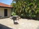 An outdoor patio features a BBQ grill, benches, and lovely palm trees providing an ideal space for outdoor entertaining at 5785 Gardens Dr, Sarasota, FL 34243