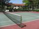 Exterior view of a community tennis court with trees and the clubhouse in the background at 5785 Gardens Dr, Sarasota, FL 34243
