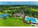 A beautiful aerial view showcases a pool, tennis court, manicured lawns, and lush landscaping within a well-maintained community at 5830 100Th E Ave, Parrish, FL 34219