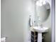 Cozy half bathroom with a pedestal sink, decorative mirror, and organized storage at 5830 100Th E Ave, Parrish, FL 34219
