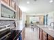 Open concept kitchen features wooden cabinetry, stainless steel appliances, and view to dining area at 5830 100Th E Ave, Parrish, FL 34219