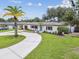 Aerial view of home with a circular driveway, lush lawn, and mature trees in a well-manicured neighborhood at 5934 51St N Ave, Kenneth City, FL 33709
