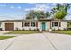 Inviting home exterior with a circular driveway, turquoise front door, and neatly landscaped front yard, ready for move-in at 5934 51St N Ave, Kenneth City, FL 33709