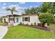 Landscaped front yard with a brick accent wall, a circular driveway, and a quaint facade with a pop of color at 5934 51St N Ave, Kenneth City, FL 33709