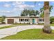 Exterior of home featuring beautiful landscaping, a circular driveway, and a bright blue front door at 5934 51St N Ave, Kenneth City, FL 33709