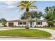 Charming ranch-style home with a circular driveway and a lush green lawn with a bright blue front door at 5934 51St N Ave, Kenneth City, FL 33709