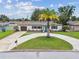 Charming single-story home with a circular driveway and a well-manicured lawn, featuring a vibrant palm tree at 5934 51St N Ave, Kenneth City, FL 33709