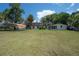 Expansive backyard with green grass, a carport, and a two-story home, offering plenty of space for activities at 6108 Oak Ridge Ave, New Port Richey, FL 34653