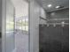 Bathroom features a modern shower with gray tile and access to the sunroom at 6108 Oak Ridge Ave, New Port Richey, FL 34653