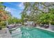 Inviting outdoor pool area with lounge seating, mature trees, and an elegant iron fence at 6220 Bayshore Blvd, Tampa, FL 33611
