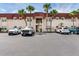 Condominium building featuring a red roof, neutral colored walls, palm trees, and parking at 6360 1St N St # 202, St Petersburg, FL 33702
