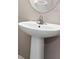 Bathroom with a white pedestal sink, oval mirror and chrome faucet showing modern design at 6909 Holly Heath Dr, Riverview, FL 33578