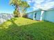 Large, grassy backyard with palm trees, fenced perimeter, and patio at 7314 Ivanhoe Dr, Port Richey, FL 34668