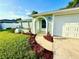 Close-up of charming front entrance with colorful mulch, landscaping, and sidewalk leading to garage at 7314 Ivanhoe Dr, Port Richey, FL 34668
