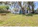 A white home with an expansive backyard featuring mature trees offering ample shade and natural beauty at 7441 Cypress Dr, New Port Richey, FL 34653