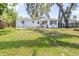 A white home with an expansive backyard featuring mature trees and an area that can be used for patio furniture at 7441 Cypress Dr, New Port Richey, FL 34653