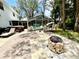 Wide shot of backyard with fire pit, patio, pool and screened enclosure and lush foliage at 8834 Whispering Oaks Trl, New Port Richey, FL 34654